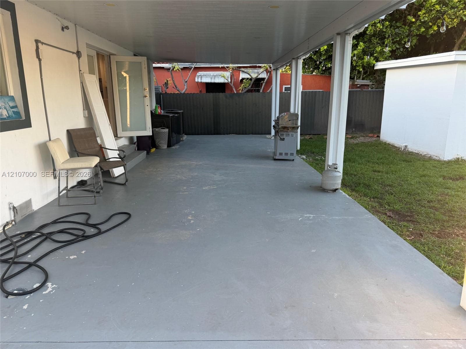 Covered concrete patio featuring painted flooring, support columns, and an outdoor wall-mounted light fixture
