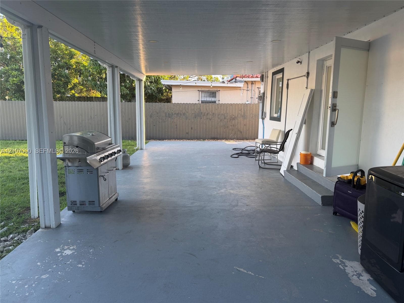 Covered concrete patio featuring recessed lighting, support columns, and an exterior entry door