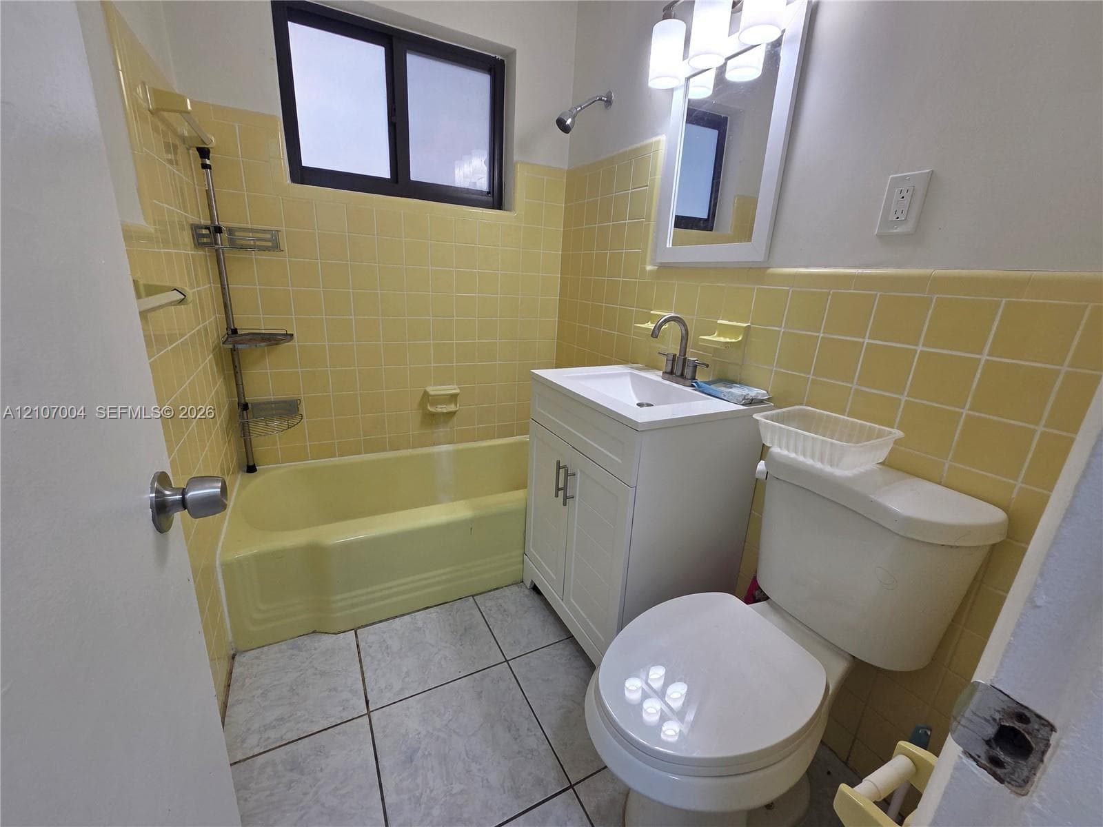 Bathroom featuring a white vanity cabinet, square porcelain sink, metal faucet, and large-format tile flooring
