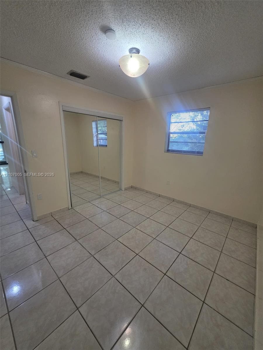 Interior space featuring ceramic tile flooring, a mirrored sliding closet door, and a single-pane window