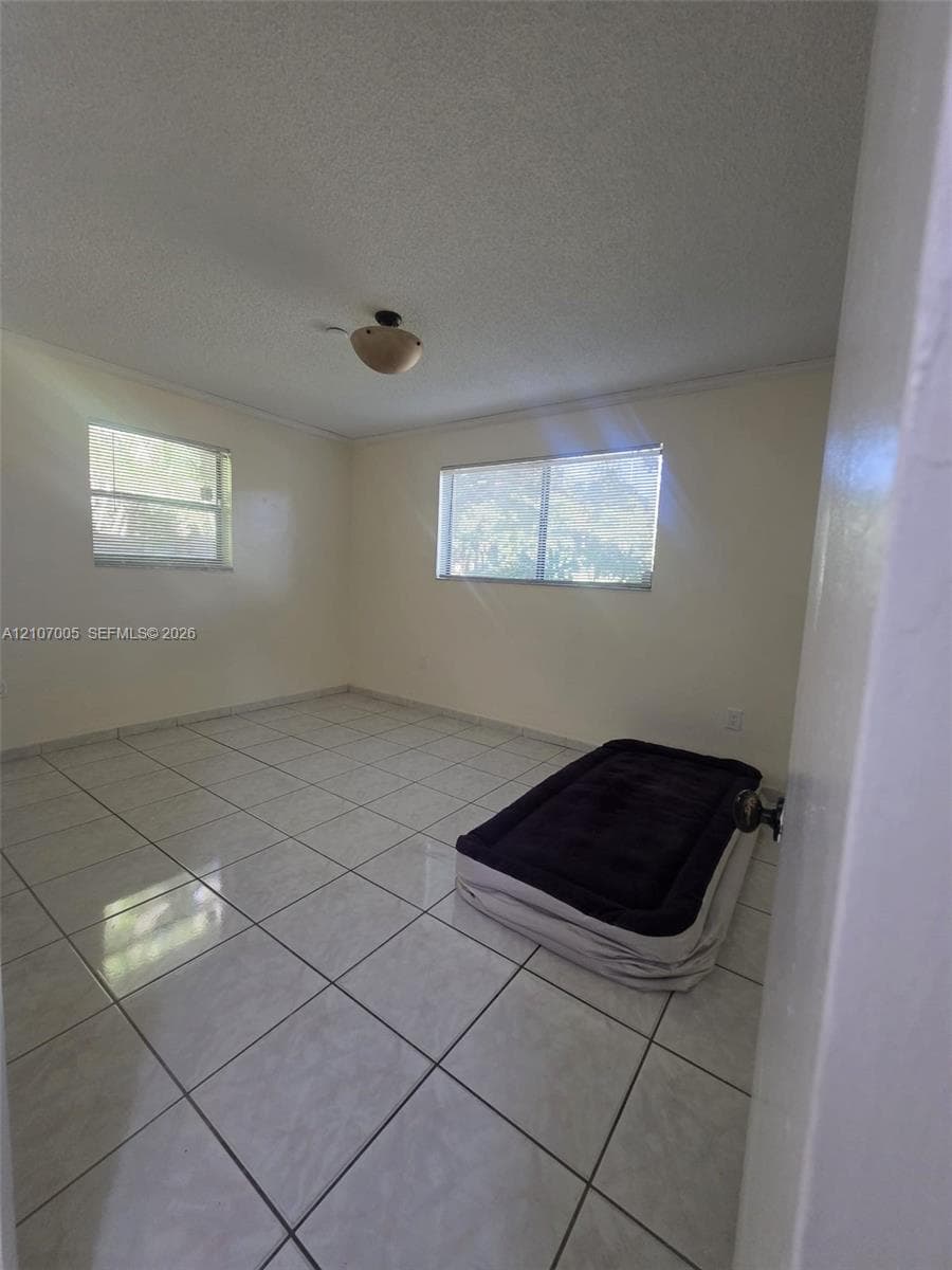 Neutral-toned interior featuring ceramic tile flooring, dual windows, and a flush-mount light fixture