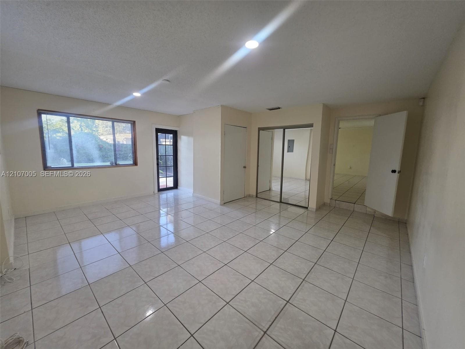 Neutral ceramic tile flooring, recessed lighting, expansive multi-pane window, exterior door with glass insert, and mirrored closet doors