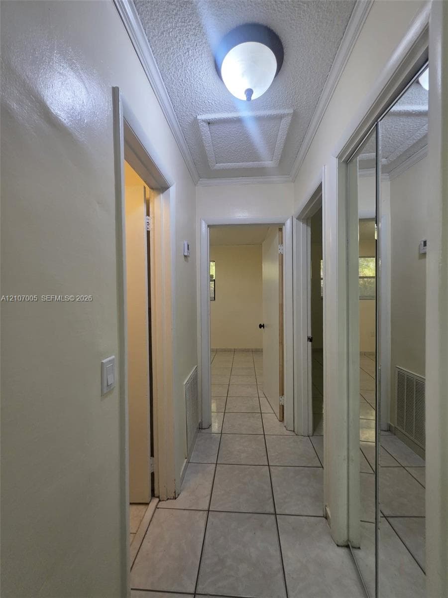Hallway featuring ceramic tile flooring, ceiling-mounted dome lighting, and mirrored closet doors