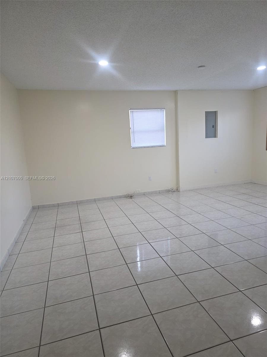 Interior space featuring neutral wall paint, high-gloss ceramic tile flooring, recessed ceiling lighting, and a single-pane window