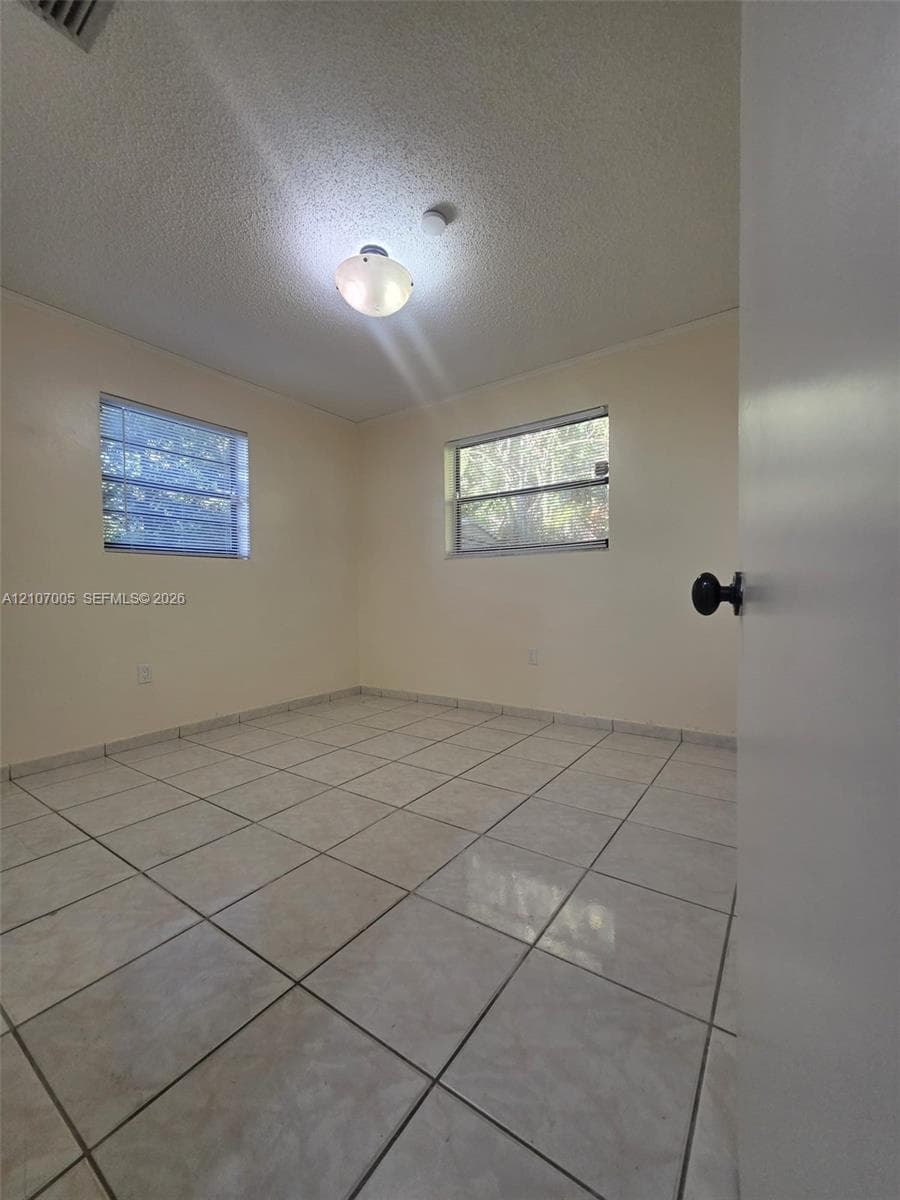 Room featuring neutral-toned ceramic tile flooring, dual-pane horizontal sliding windows, and a central flush-mount dome light fixture