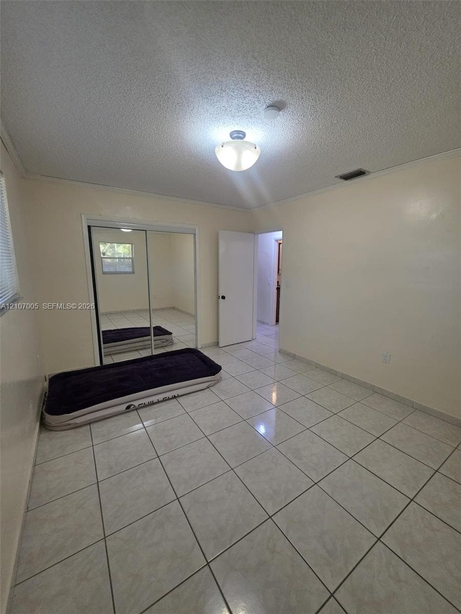 Ceramic tile flooring, sliding mirror-paneled closet doors, and a flush-mount ceiling light fixture