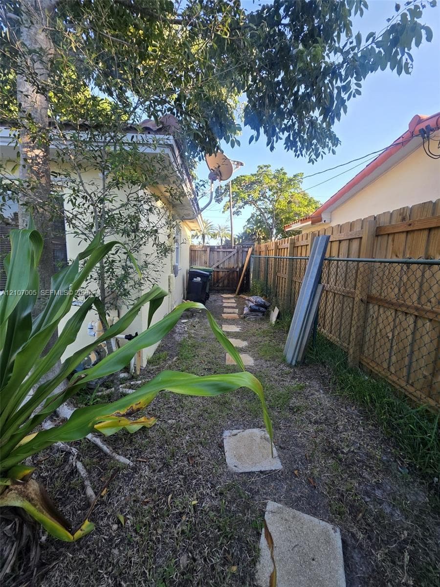 Side yard featuring concrete paver path, wood fencing, and tile roofline