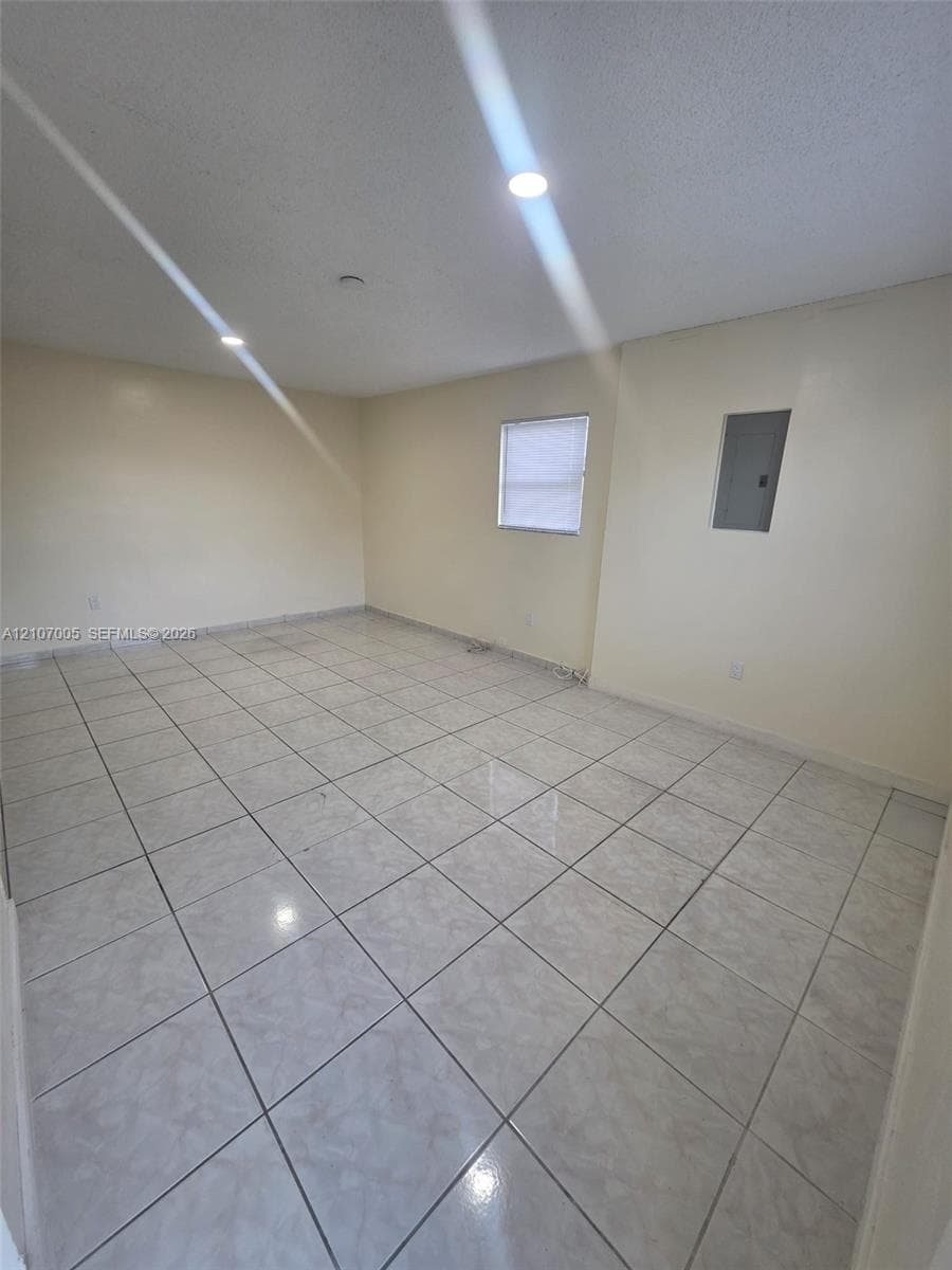 Neutral-toned ceramic tile flooring, recessed ceiling lighting, and a single-pane window with installed blinds
