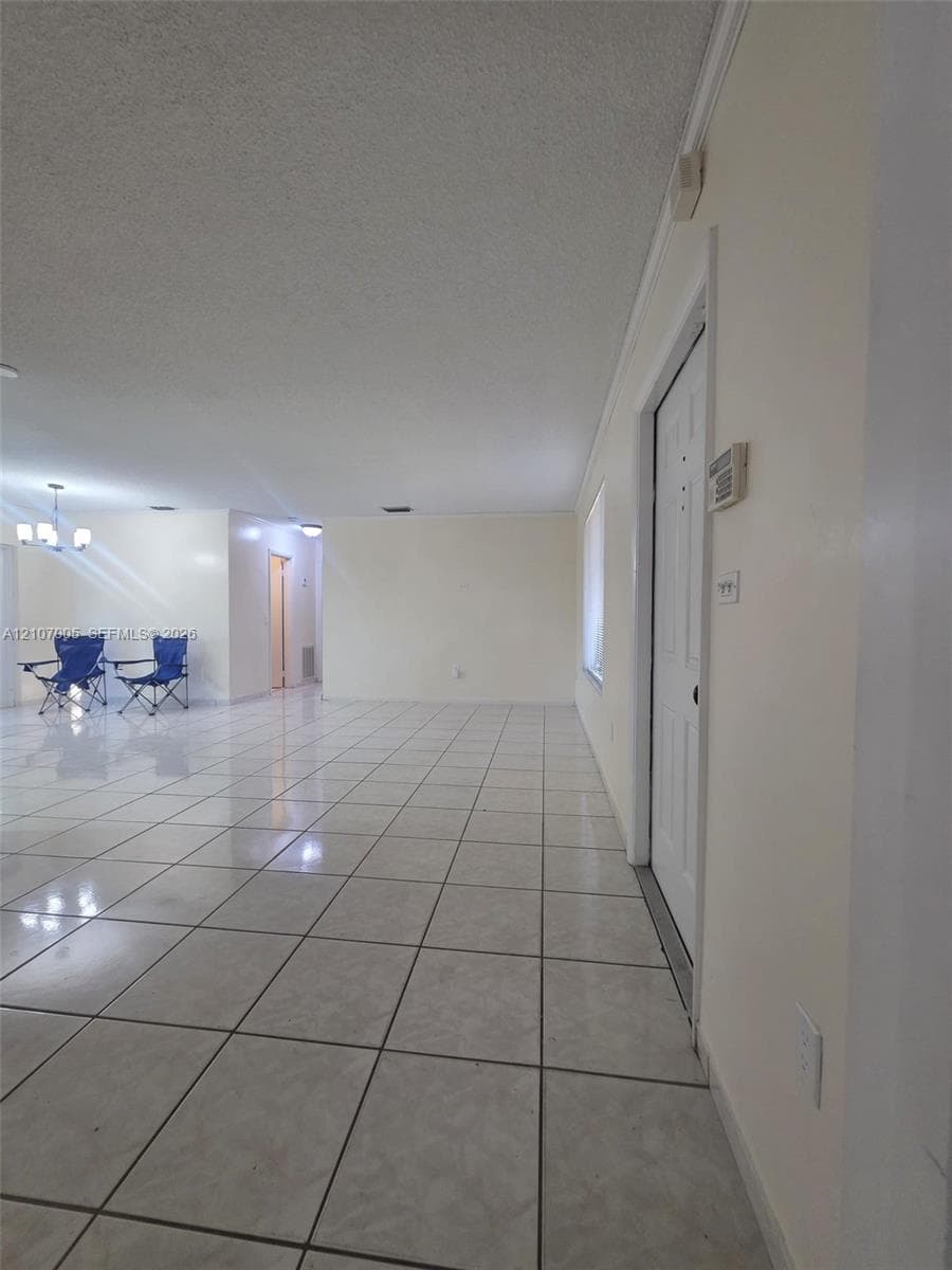Large interior space featuring light-colored tile flooring, neutral wall tones, multi-panel doors, and integrated lighting fixtures