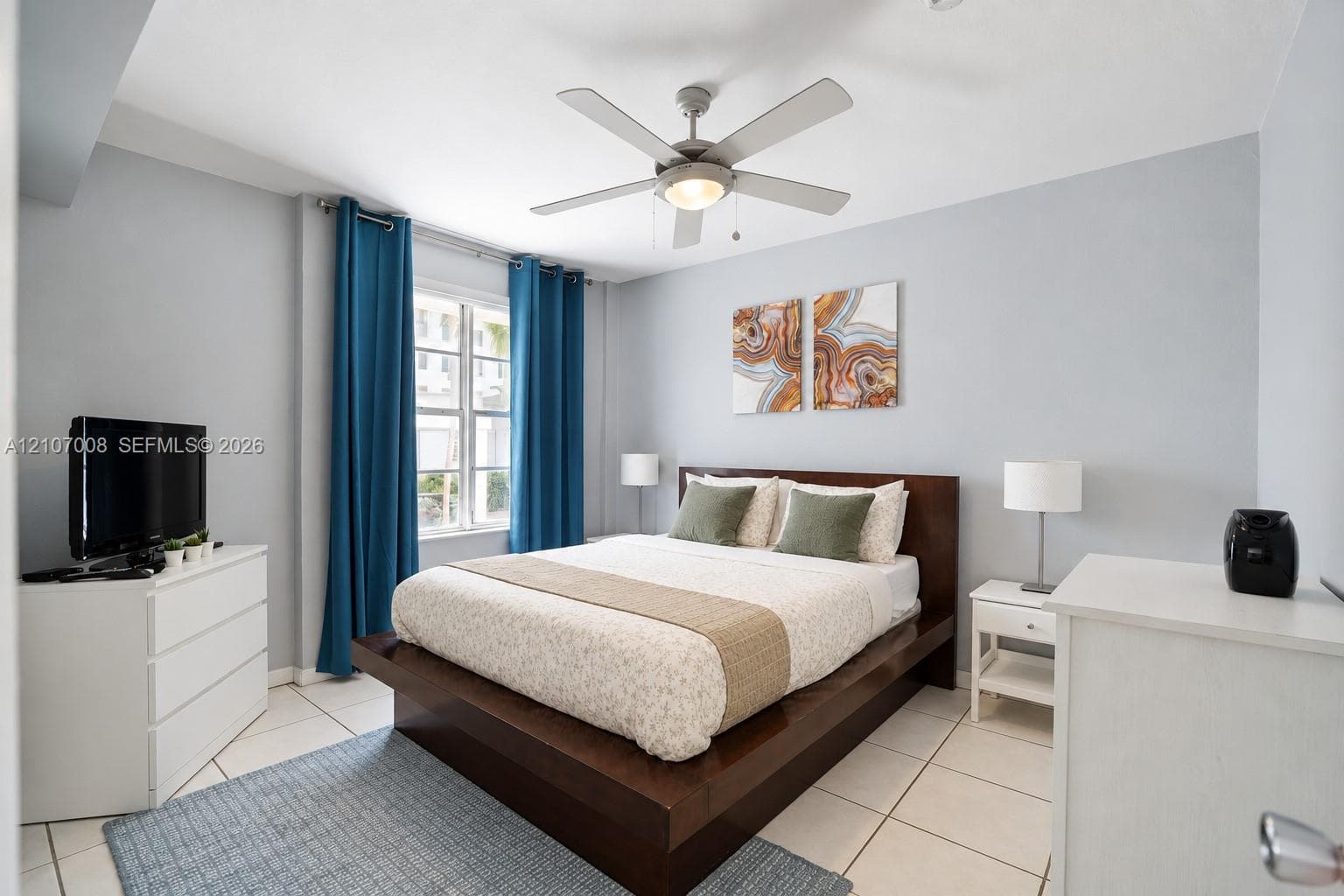 Light-filled room featuring large format tile flooring, a multi-blade ceiling fan with integrated lighting, and a multi-pane window