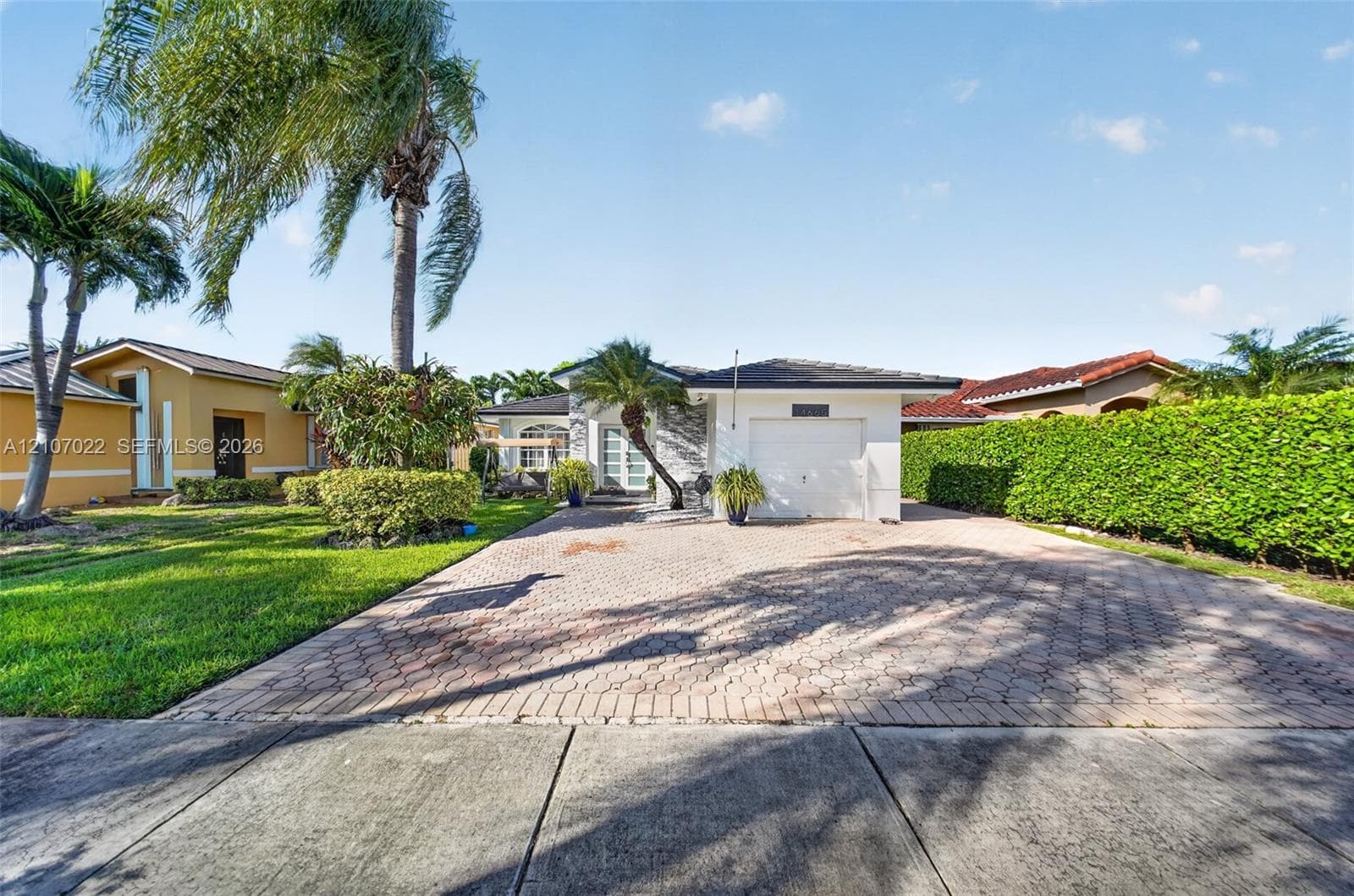 Single-story residence featuring a paved brick driveway, attached garage, stone-accented facade, ample parking
