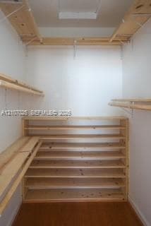 Walk-in storage space featuring wood-finish flooring and extensive integrated multi-tier wood shelving