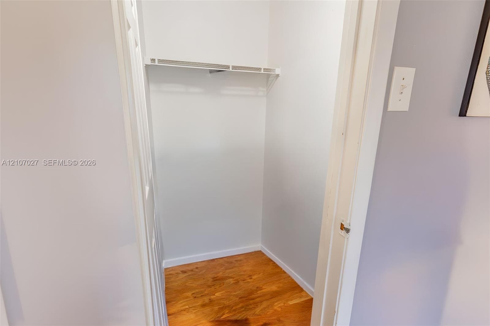 Storage closet featuring wood-finish flooring and an installed wire shelf