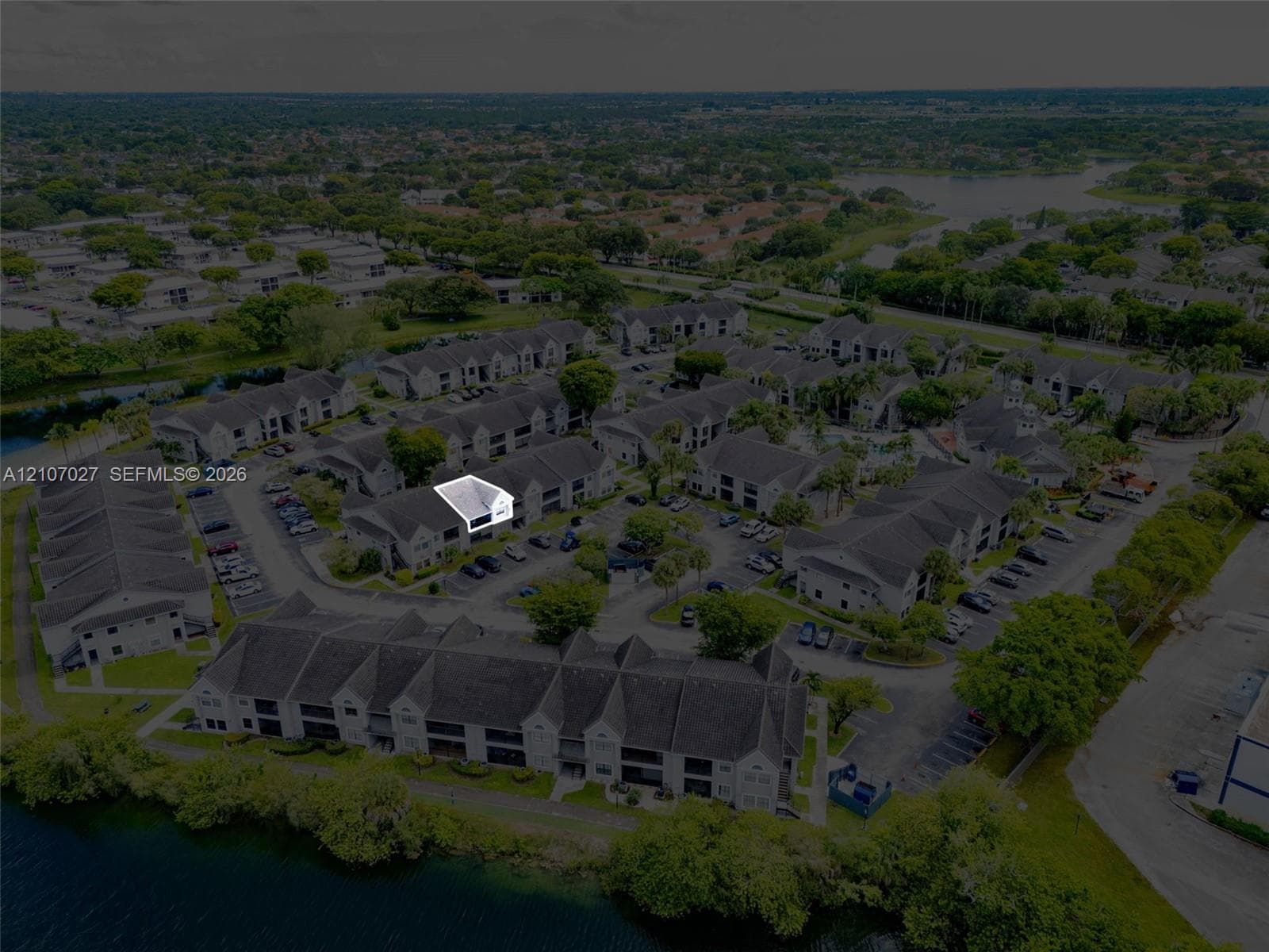 Aerial perspective of a multi-unit residential complex featuring gabled roofs, asphalt shingles, and paved surface parking