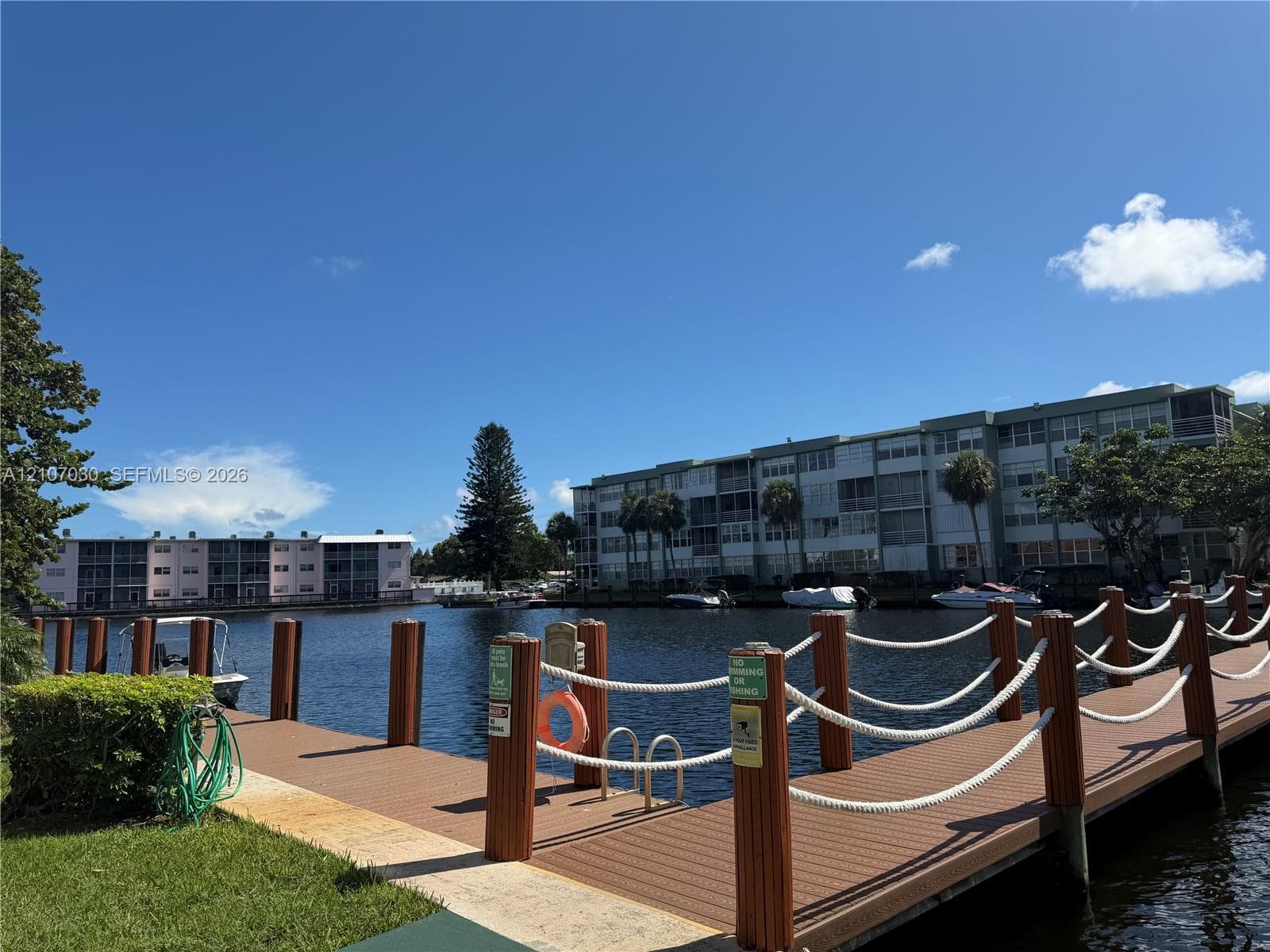 Waterfront dock featuring composite decking, vertical posts with rope railings, and a built-in swimming ladder