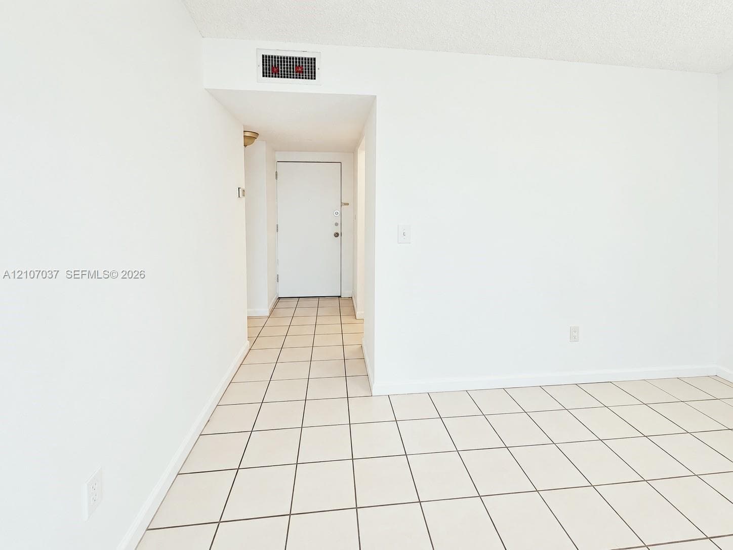 Interior space featuring large-format ceramic tile flooring, neutral walls, and a sliding glass door opening to a private balcony
