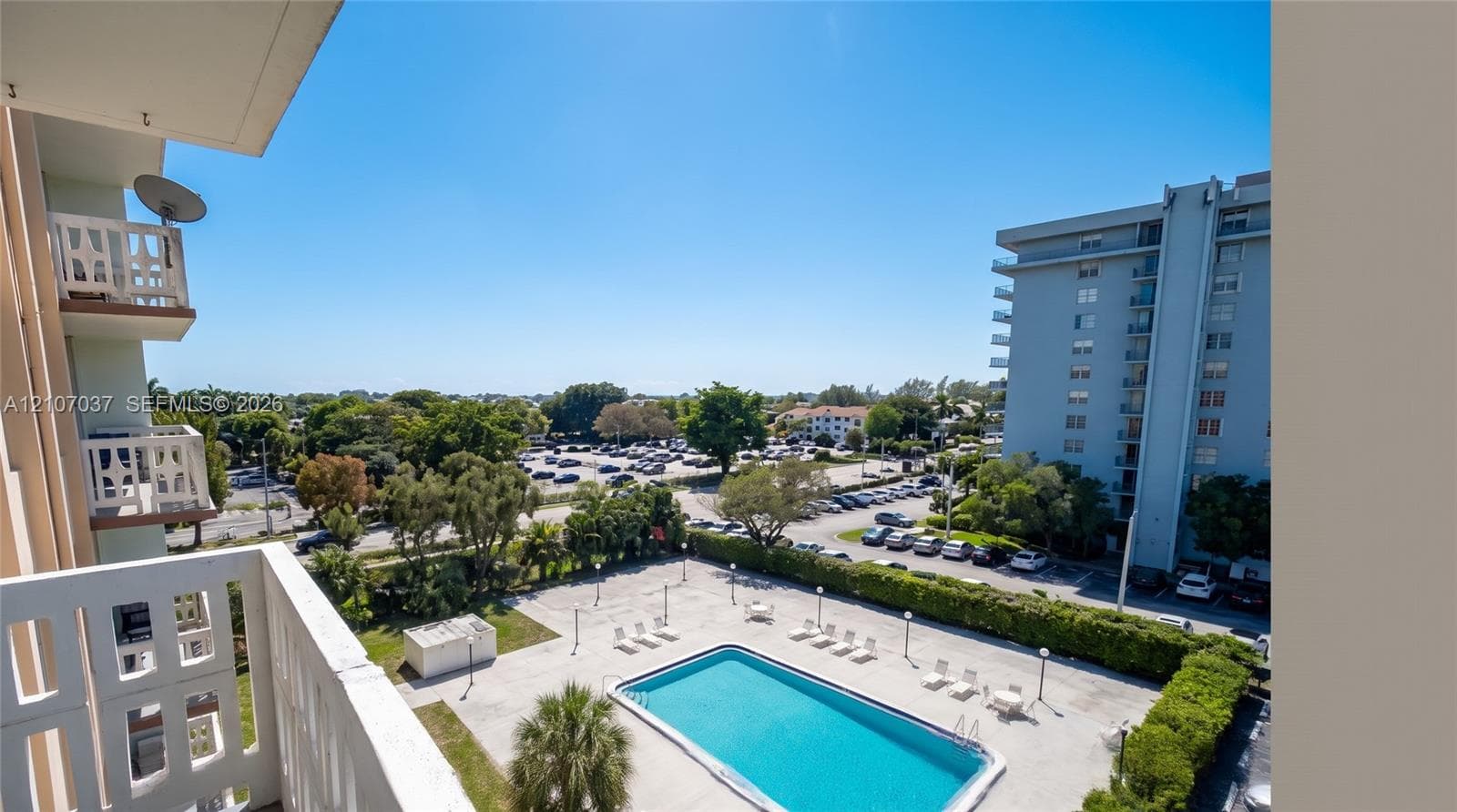 Private balcony with decorative masonry railings overlooking an outdoor swimming pool and paved deck area