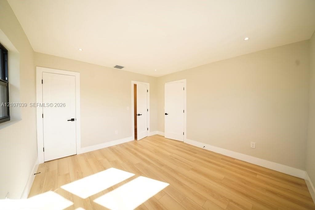 Neutral-toned walls, wood-finish flooring, recessed lighting, and white interior doors with matte black hardware