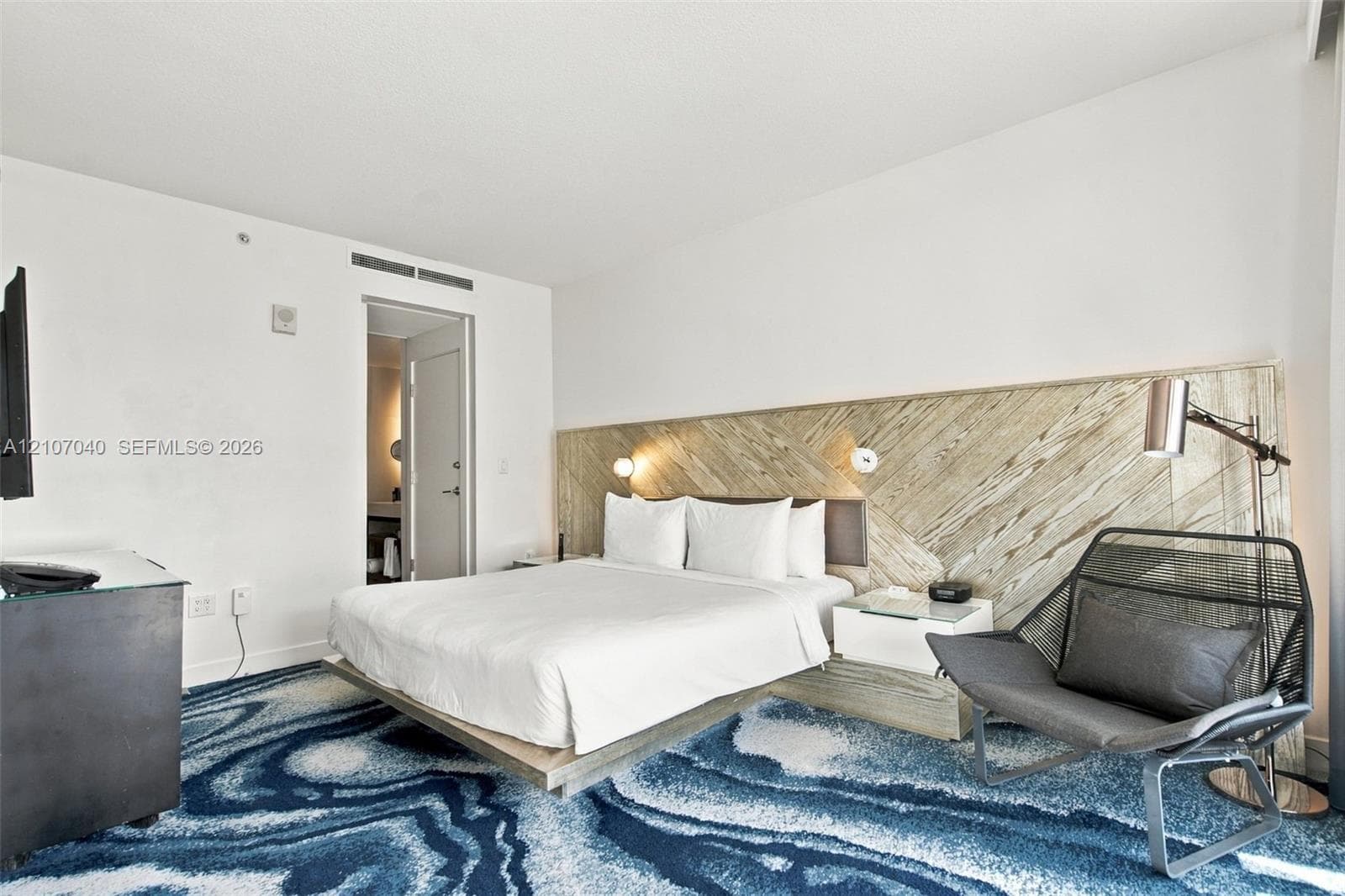 Bedroom featuring a diagonal wood-finish accent wall, built-in floating nightstands, and wall-mounted reading lights