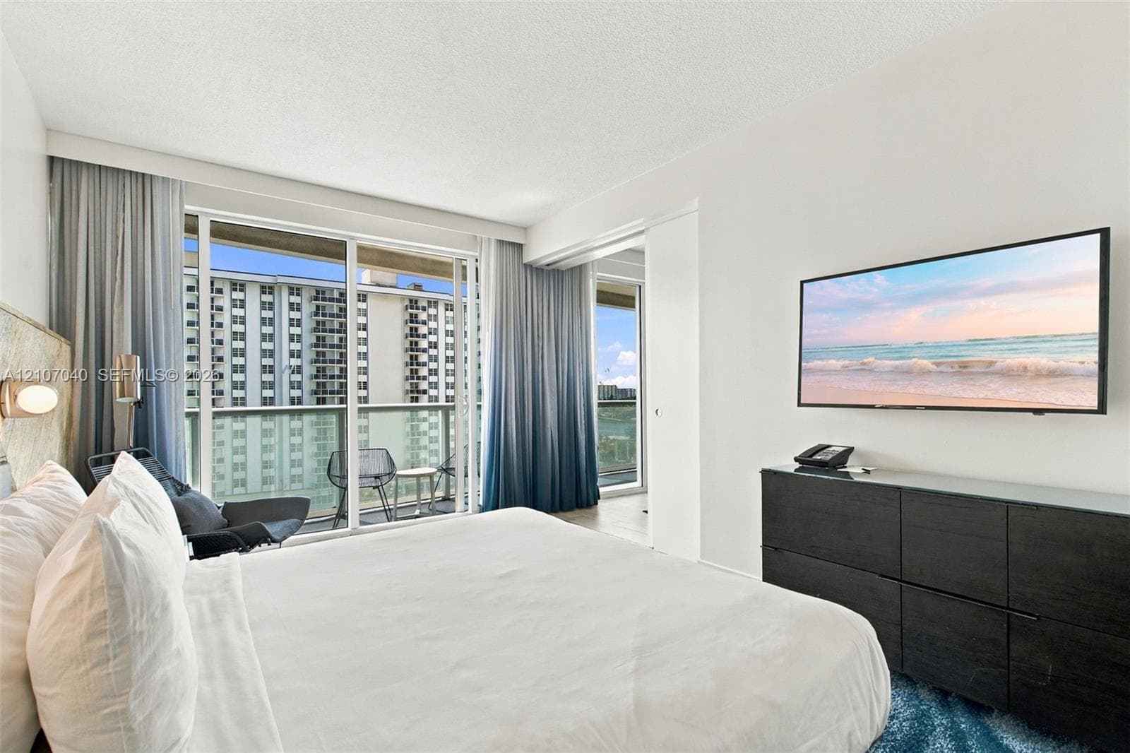 Floor-to-ceiling glass sliding doors, private balcony access, and crisp white wall finishes