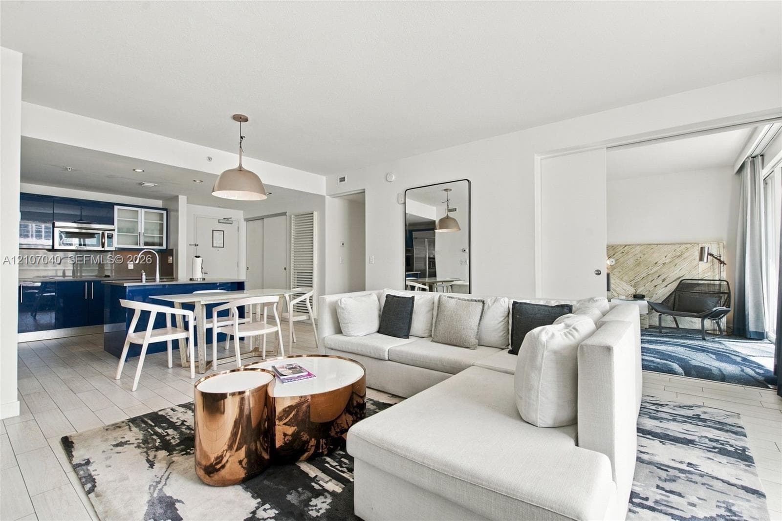 Open-concept kitchen featuring high-gloss navy cabinetry, stainless steel appliances, and a central island with a built-in sink