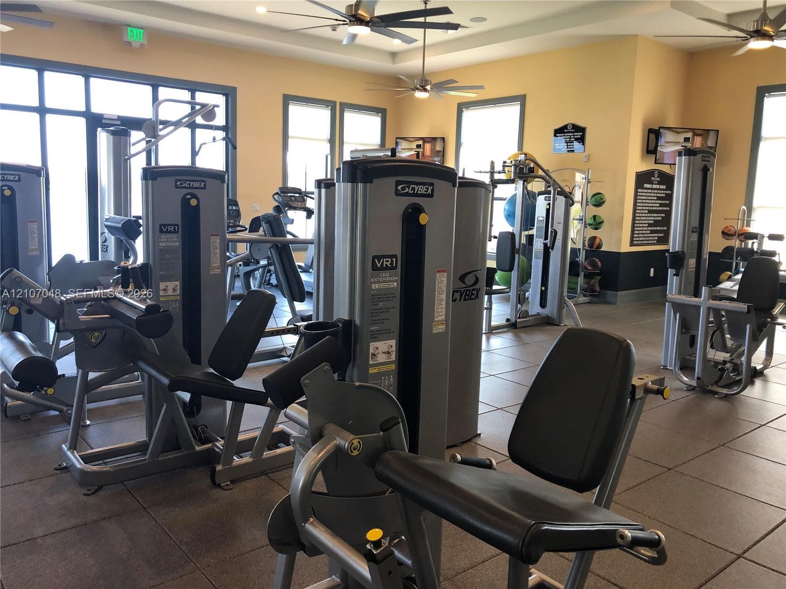Fitness center featuring large-format ceramic tile flooring, multiple integrated ceiling fans, and expansive windows