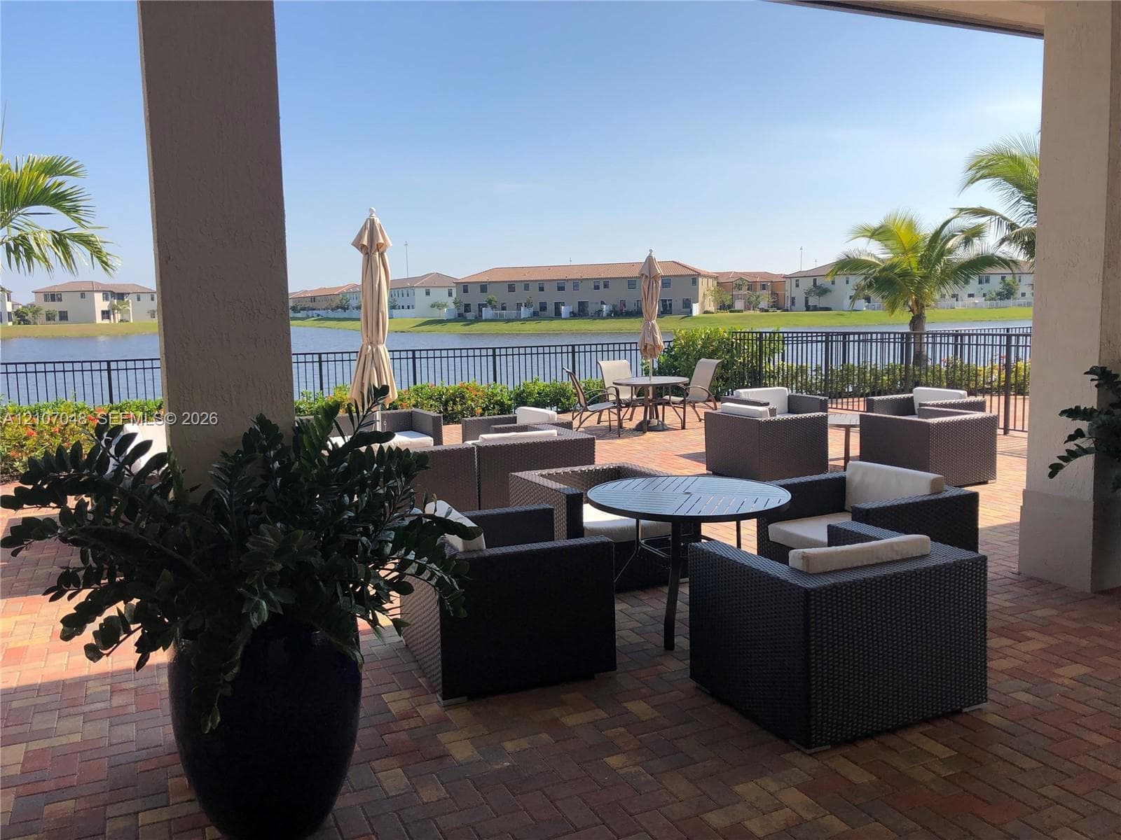 Covered patio with brick paver flooring, metal railing enclosure, and waterfront exposure
