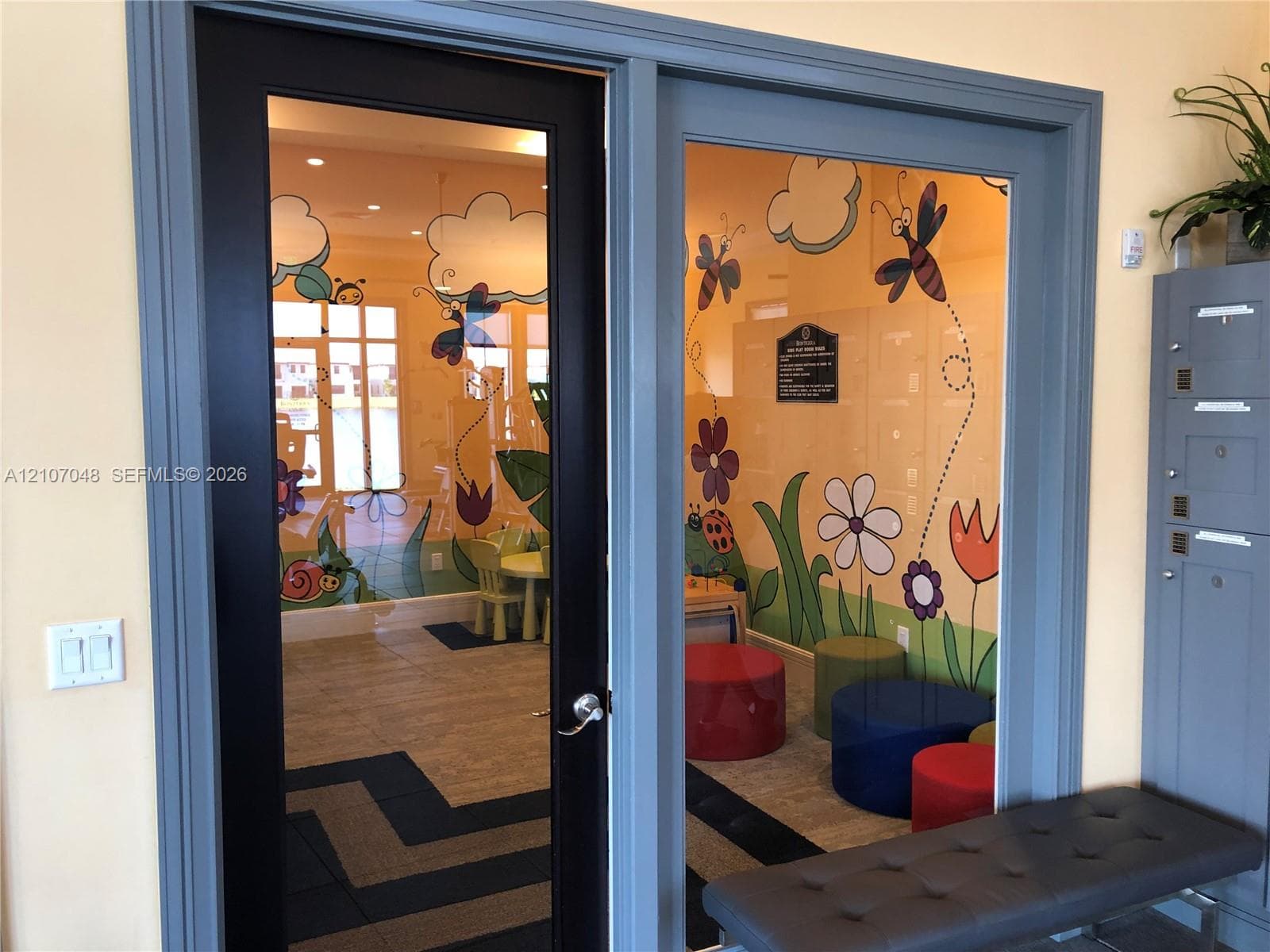 Glass-panel door with a black frame, metal locker unit, and neutral tile flooring
