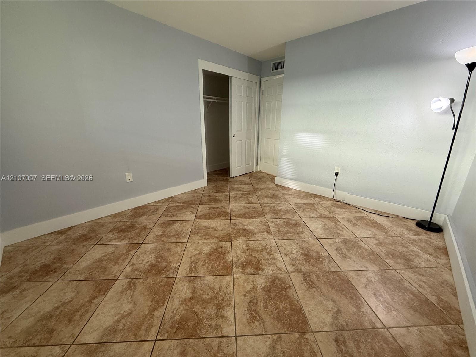 Neutral-toned tile flooring, light-colored wall finish, dual-panel interior door, and built-in closet with sliding doors