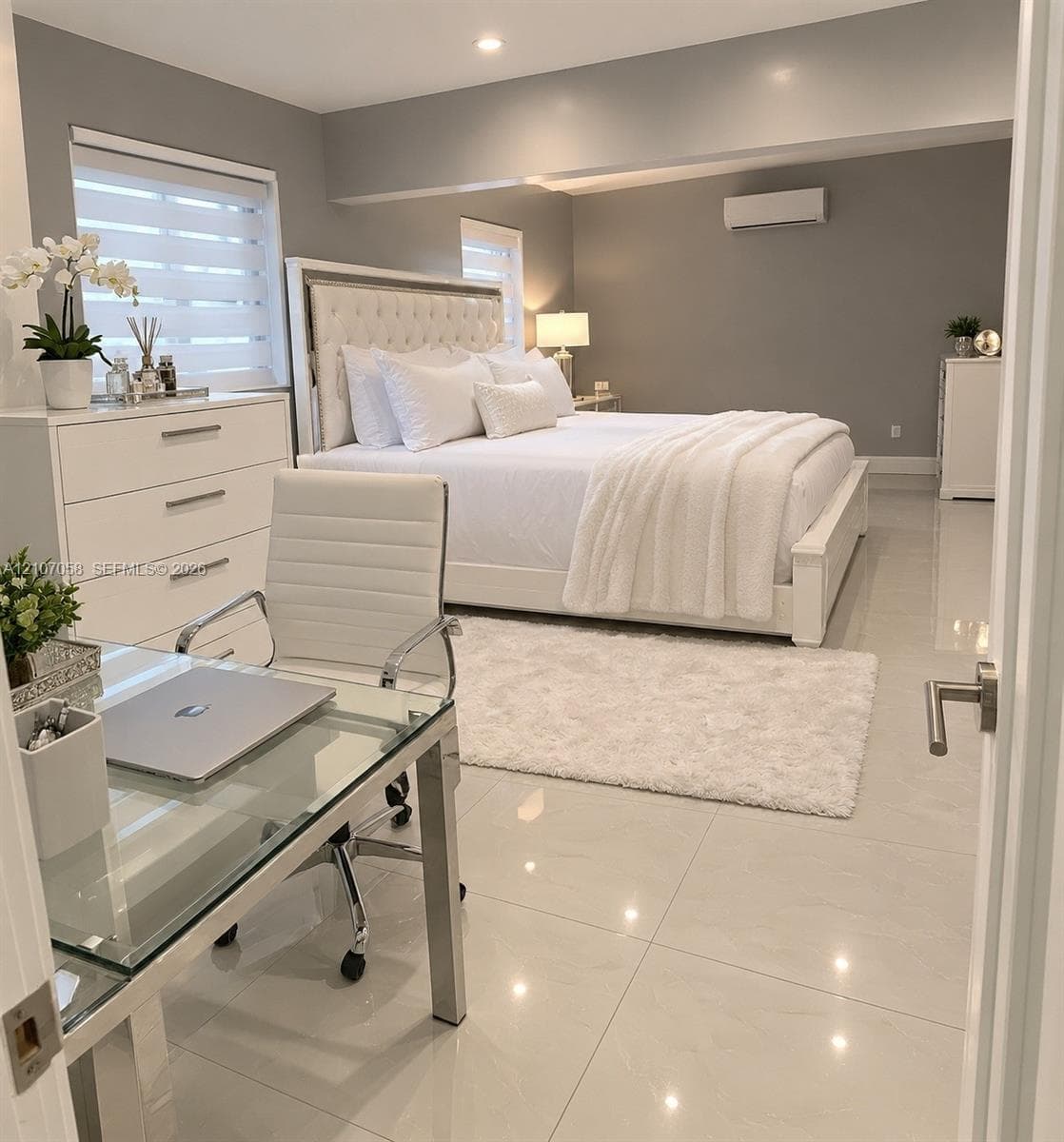 Large-format tile flooring, recessed ceiling lighting, wall-mounted ductless climate control unit, and window treatments with horizontal blinds