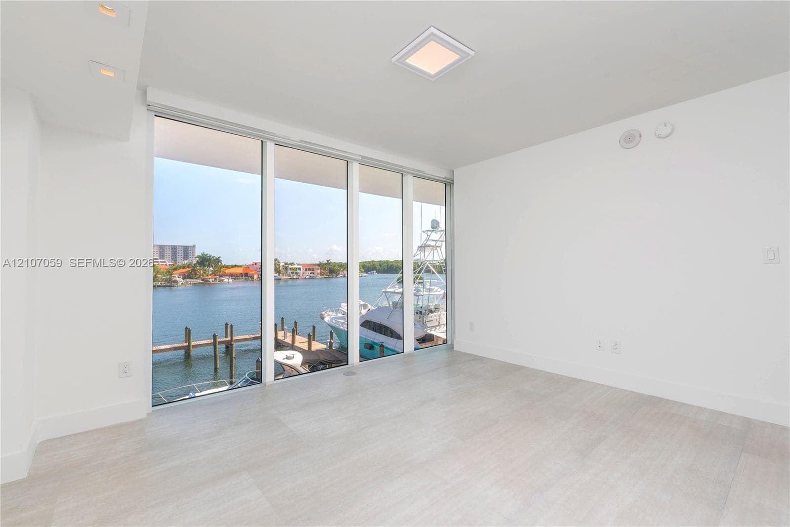 Floor-to-ceiling windows featuring water frontage, wood-finish tile flooring, recessed lighting, and a square flush-mount ceiling fixture