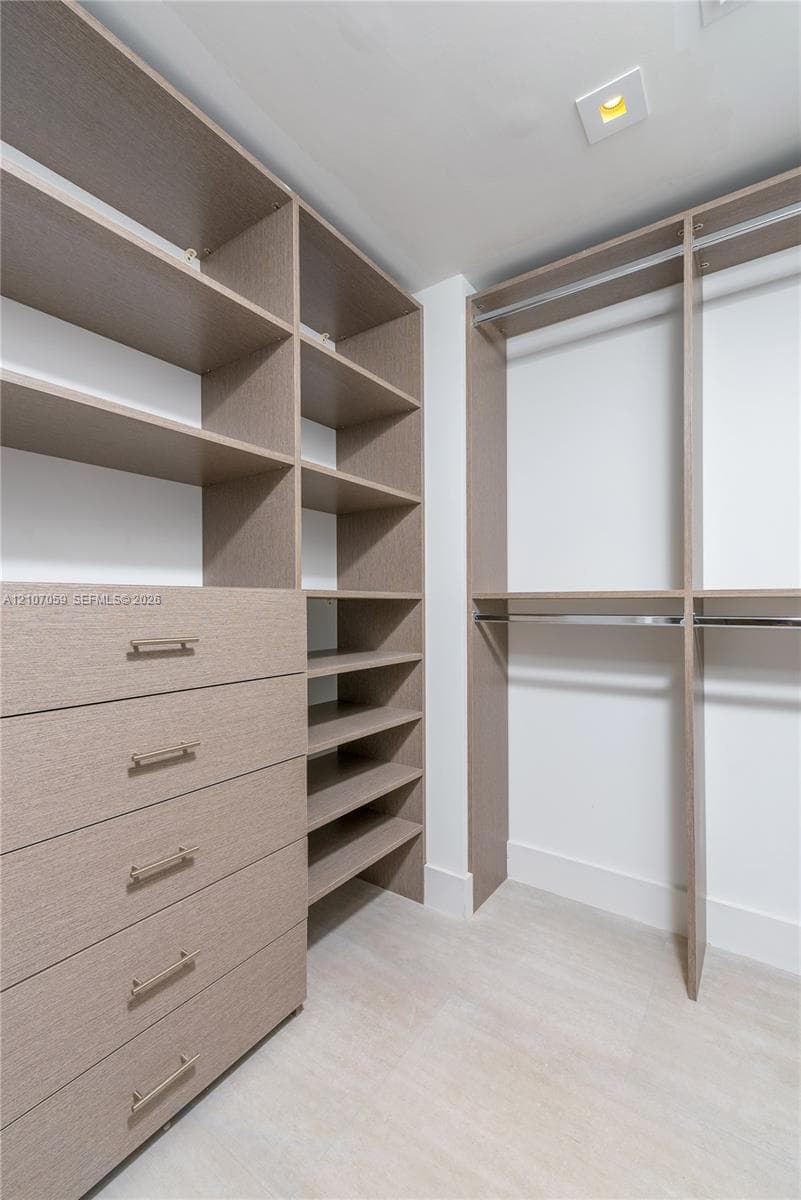 Custom walk-in closet featuring floor-to-ceiling wooden cabinetry, built-in drawer units, adjustable shelving, and integrated metal clothing rods