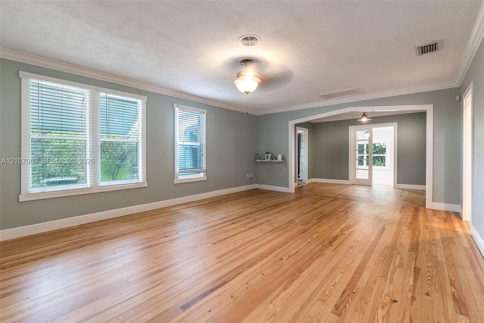Hardwood flooring, crown molding, arched room entry, and multi-pane glass door