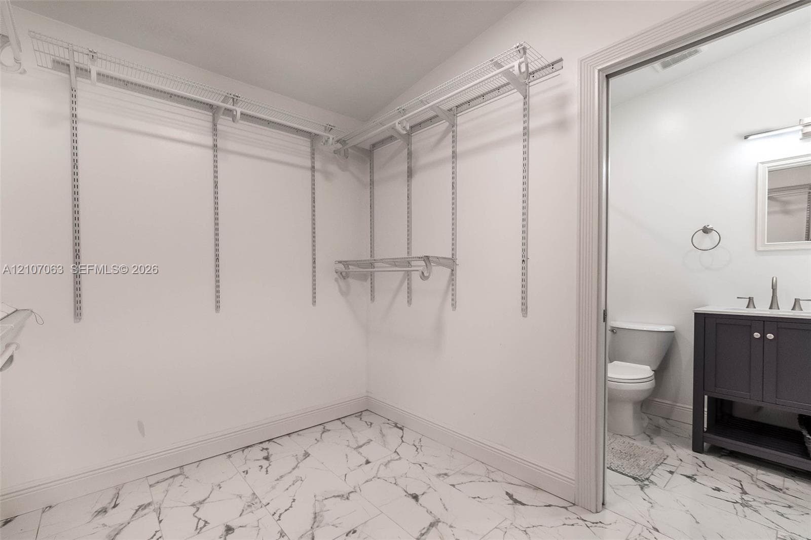 Walk-in closet featuring adjustable wire shelving and stone-pattern flooring