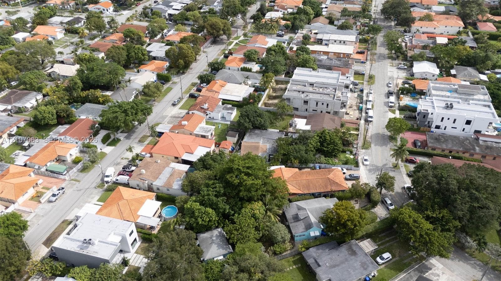 Aerial perspective of a residential neighborhood featuring paved streets, mature tree canopy, and established landscaping