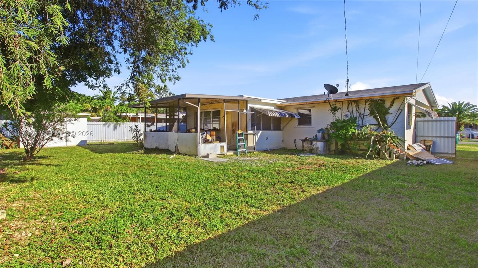 Backyard featuring a grass lawn, enclosed porch, and perimeter fencing