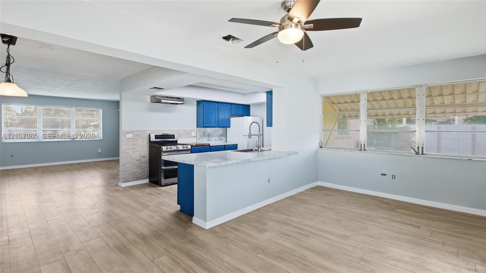 Kitchen featuring a breakfast bar with stone-look countertop, cabinetry with blue finish, stainless steel range, and wood-finish flooring
