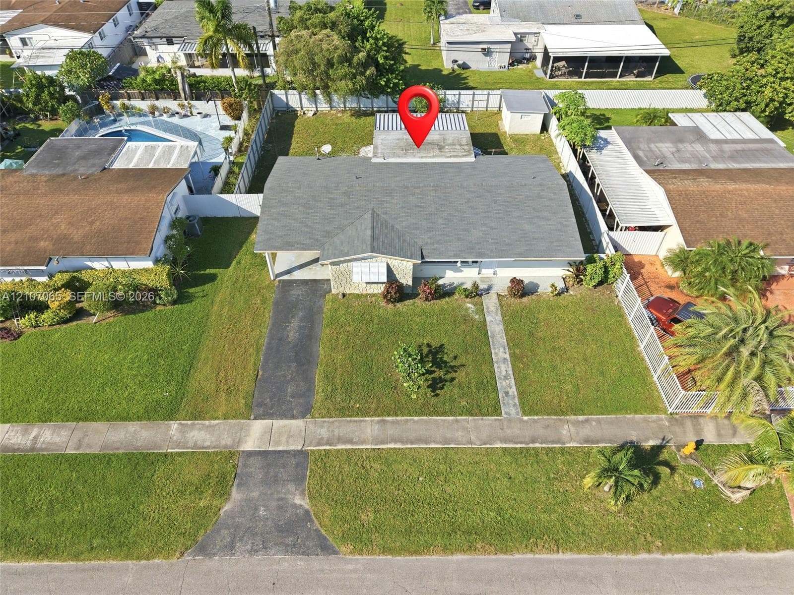 Single-story residence featuring a shingled roof, stone-veneer exterior facade, concrete driveway, and a fenced perimeter