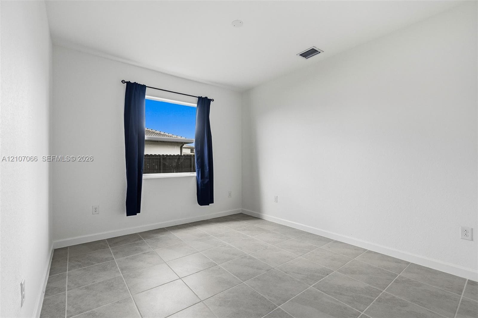 Room featuring large-format ceramic tile flooring, smooth white wall finishes, and a single-pane window