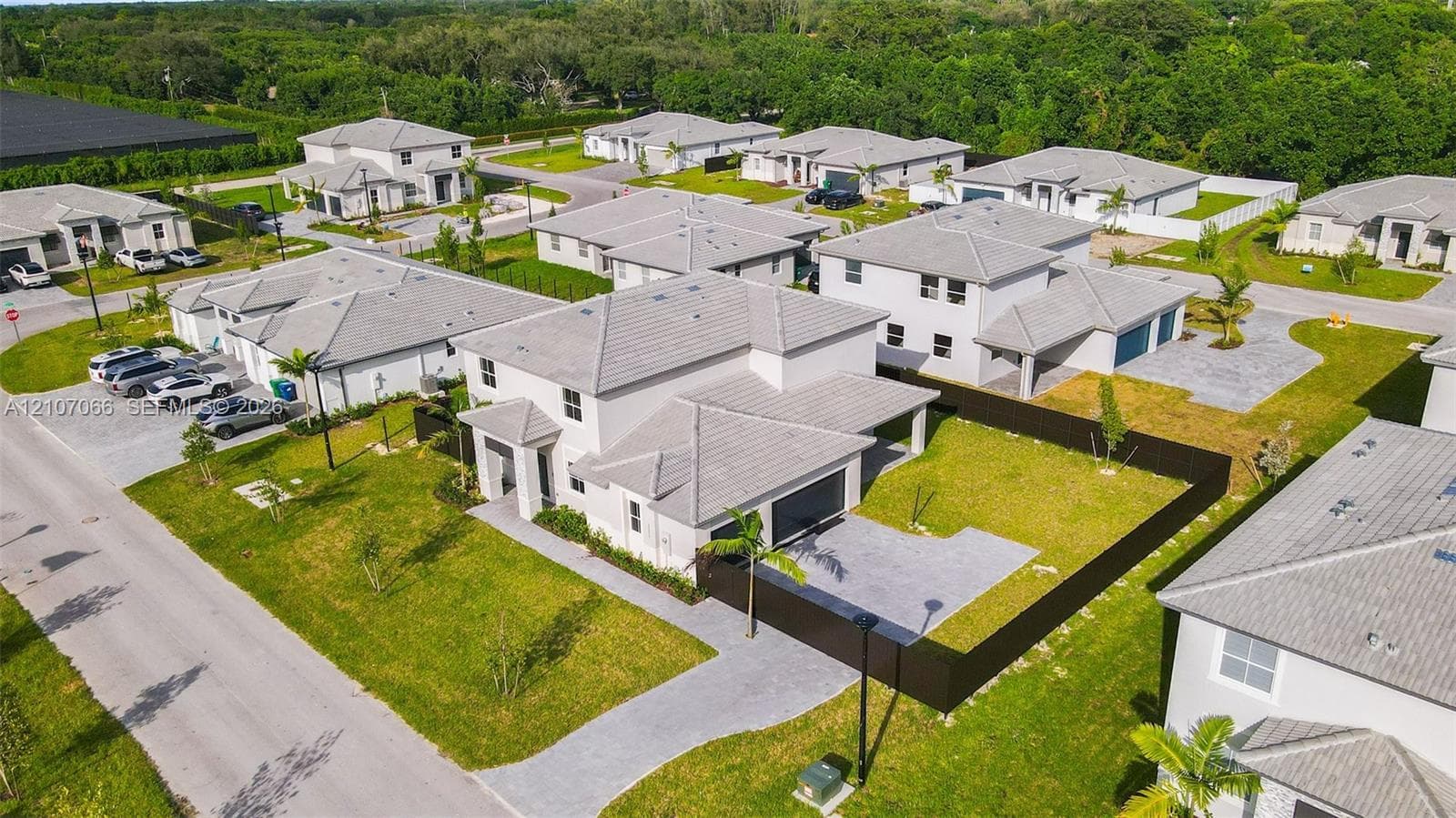 Two-story residence featuring a concrete tile roof, attached garage, paved driveway, and a fenced backyard