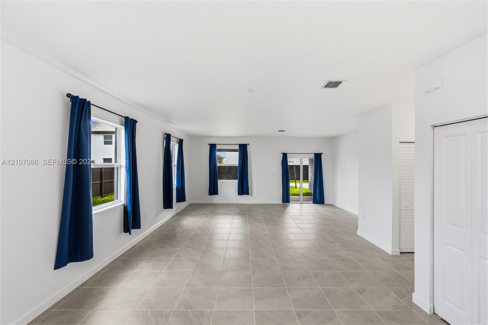 Spacious interior featuring large-format ceramic tile flooring, neutral wall finishes, and glass panel doors