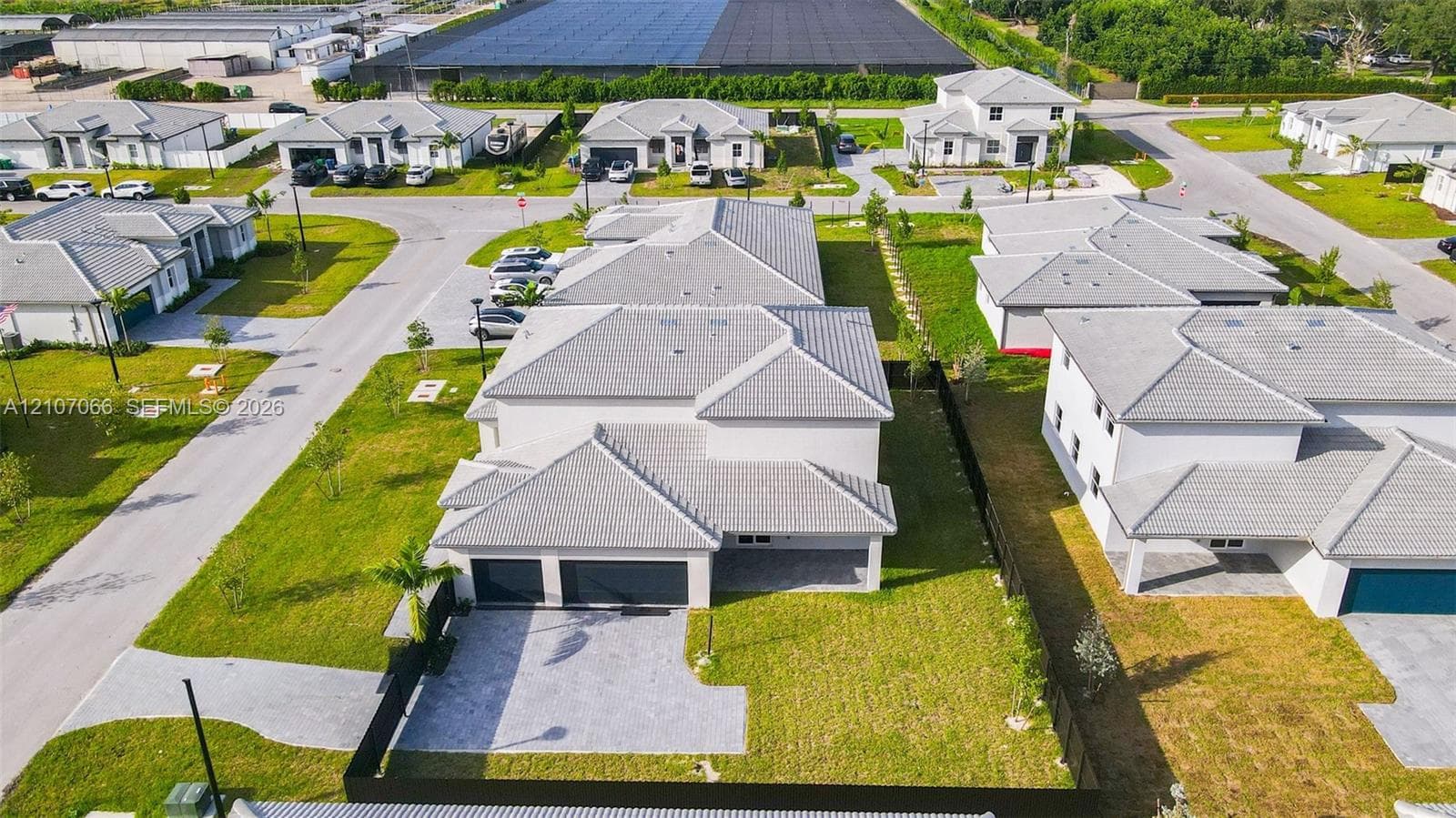 Two-story residence featuring a tile roof, light-toned exterior finish, two-car garage, and a paved driveway