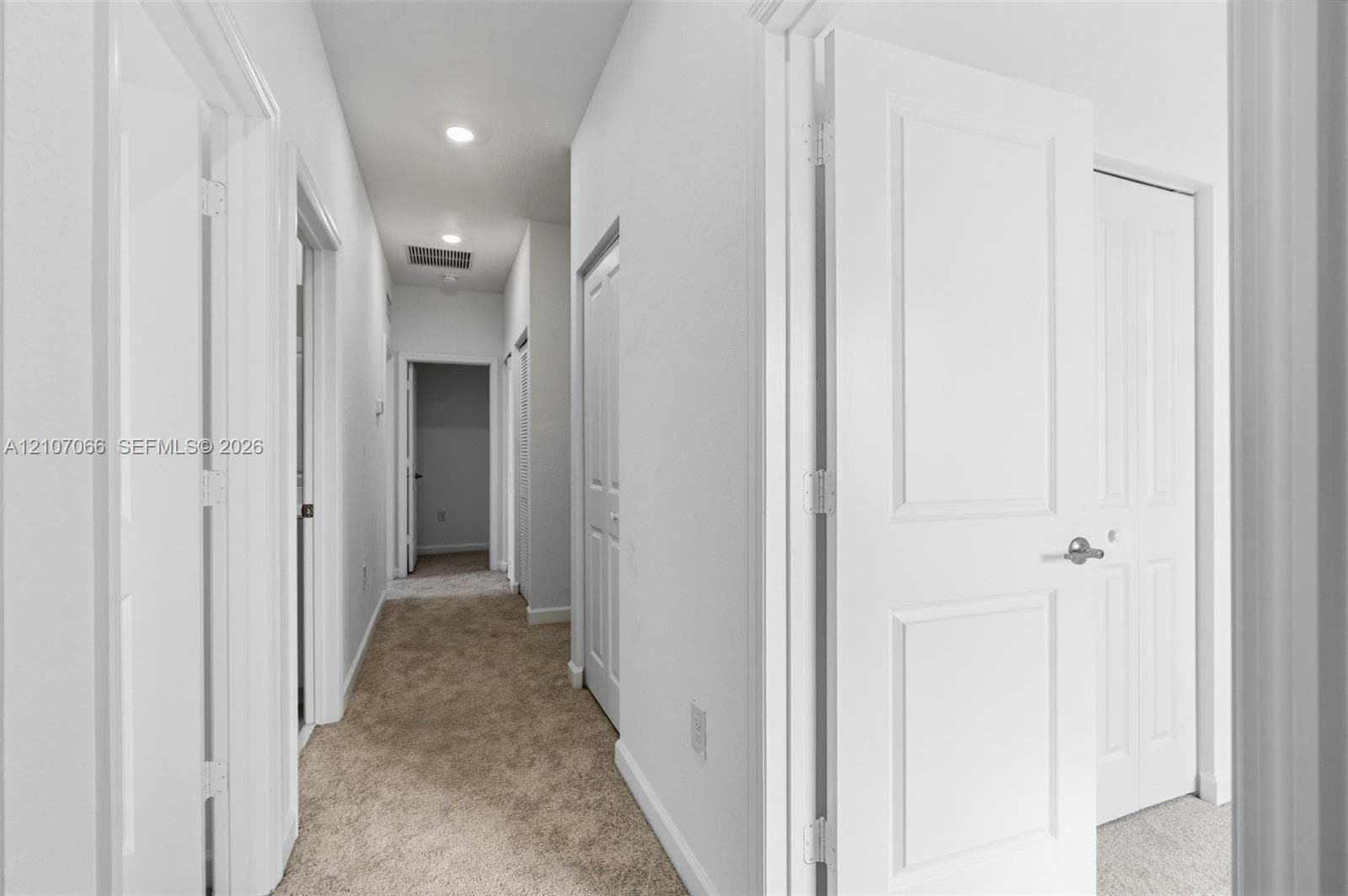 Neutral-toned carpeting, recessed ceiling lighting, and solid-core interior doors with satin nickel hardware