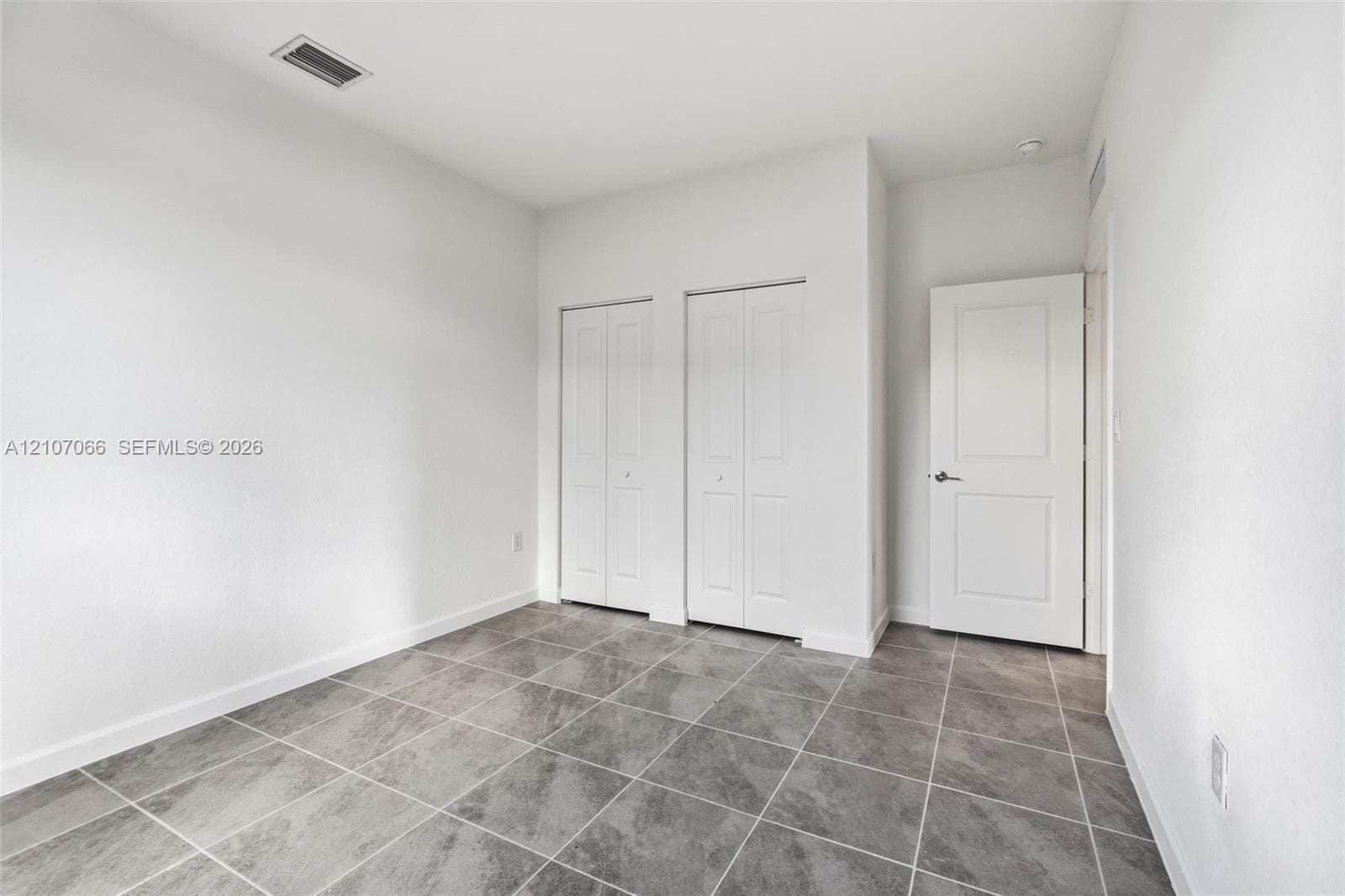 Neutral-toned tile flooring, dual-panel closet doors, and a solid-core interior door