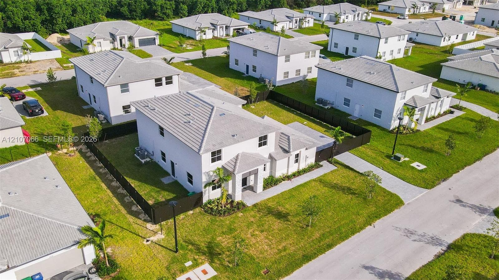 Two-story residence featuring a light-colored stucco exterior, a neutral-toned tile roof, an enclosed backyard with privacy fencing, and a concrete driveway