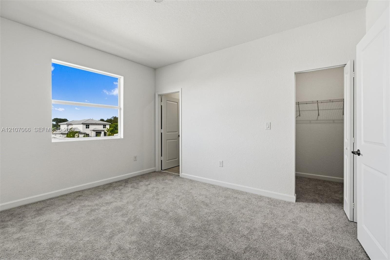 Neutral-toned carpeting, single-hung window, white interior doors, and built-in closet shelving