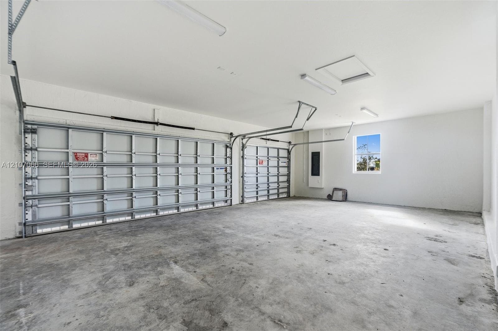Multi-car garage featuring a concrete floor, two metal sectional overhead doors, interior recessed lighting, and a window