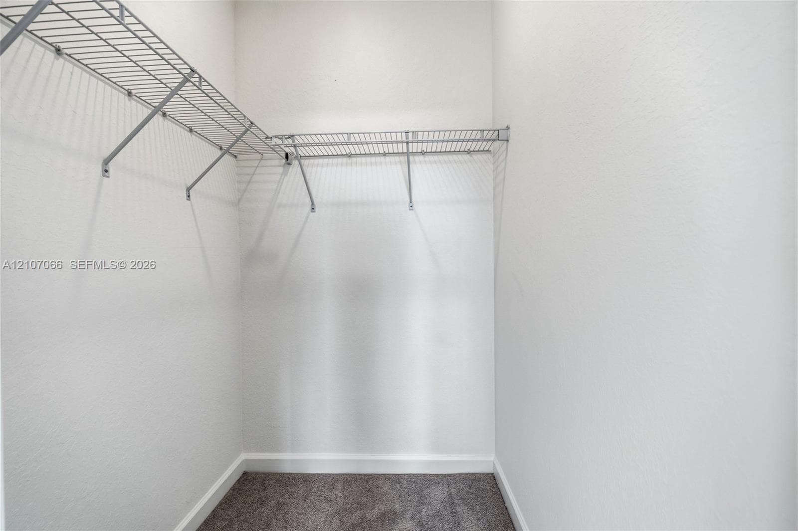 Storage space featuring tiered wire shelving and neutral carpeting
