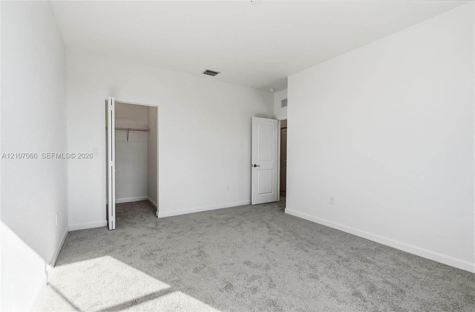 Neutral-toned carpeted flooring, white interior walls, and an interior closet with bi-fold doors