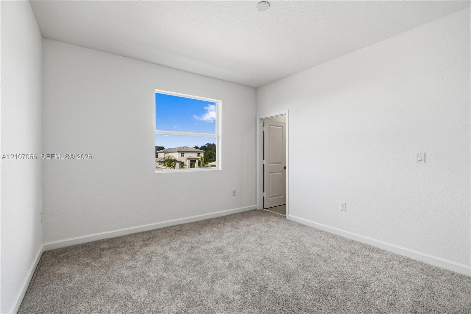Neutral interior featuring plush wall-to-wall carpeting, crisp white wall finish, single-pane window, and white interior door